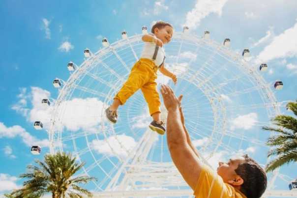father throwing kid in air in front of Orlando ICON