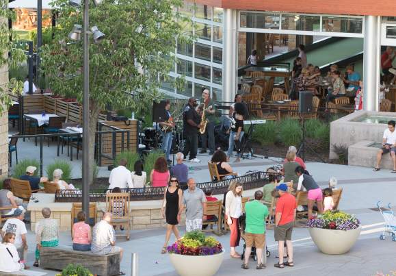 A brass band plays while people walk by and enjoy the music.