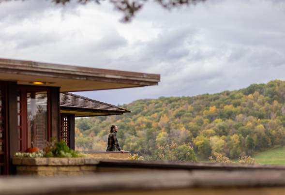 A woman looks out onto the rolling hills of Spring Green from the balcony at Taliesin