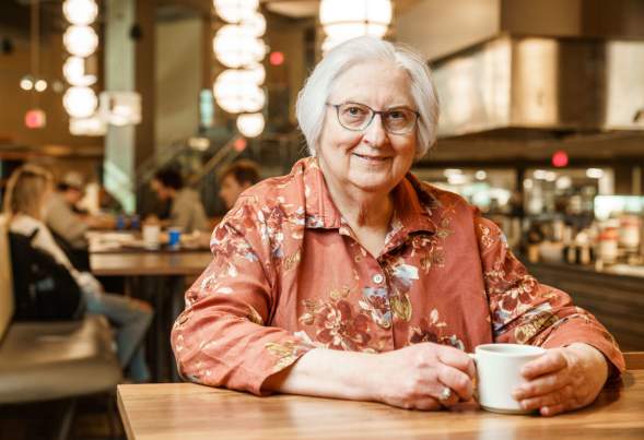 Dr. Mary Malt sits at a table with a beverage at a Kansas State Dining Hall