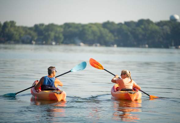 A man and a woman kayak away from the camera on Lake Mendota
