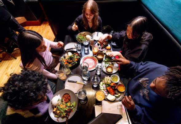 A group of five men and women gather around a table to eat Laotian food at Ahan