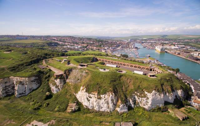 Aerial view of the grounds and red brick buildings of Newhaven Fort with sea in the distance