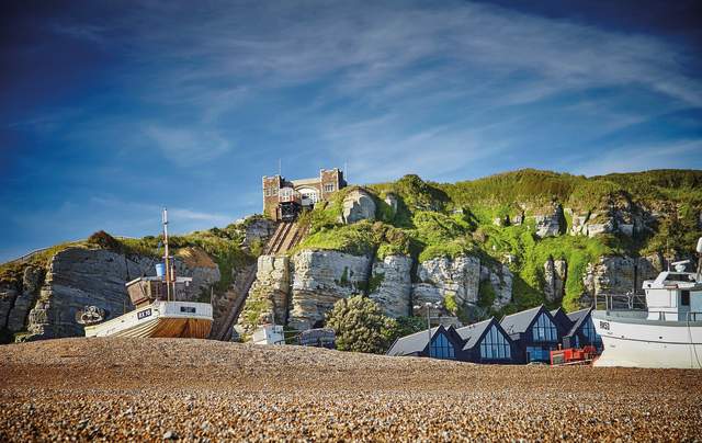 Shingle beach and fishing boat in Hastings Old Town, with cliffside lift in the background