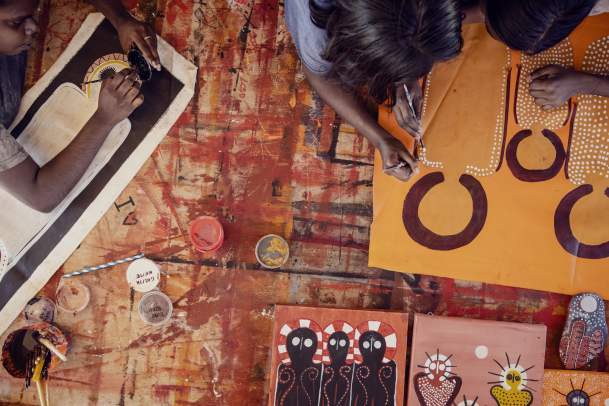 An overhead view of artists at work on a canvas at Imintji Art Centre in the Kimberley