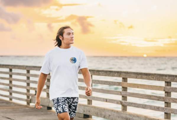 Model in beachgoing outfit strolls along pier at sunrise