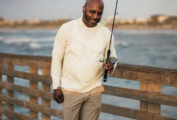 Male model walks along pier holding a fishing pole