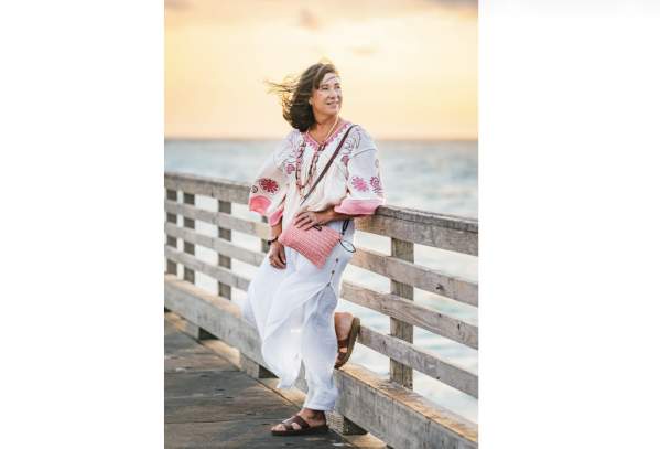Woman in pink and white outfit leans against pier fence