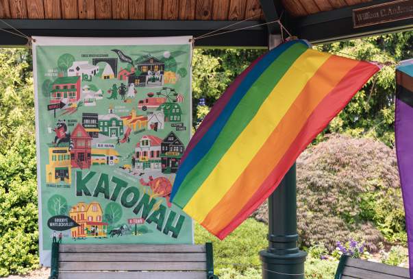 A Pride flag is gently blowing in the wind in front of a sign that reads "Katonah."