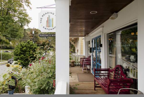 The porch of the Katonah reading room surrounded by rose bushes and with red bench seating.