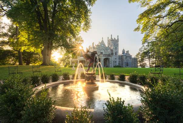 The sun sets over the Hudson River behind Lyndhurst Mansion.