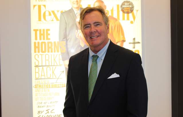 David B. Dunham in a suit posing in front of a Texas Monthly magazine cover projection.