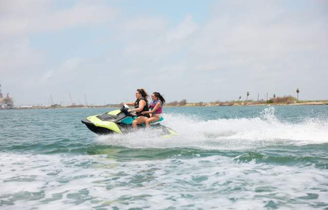 Woman and girl ride on a green jet ski