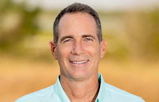 Headshot of a man in a light teal shirt that says Harte Research Institute
