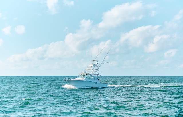 Large white charter boat in turquoise water and bright blue sky