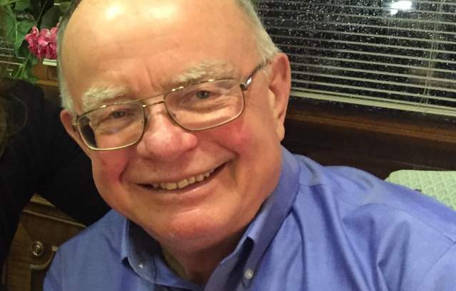 Photograph of a smiling older man in a blue button up