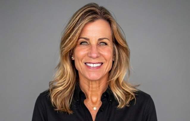 Kathleen Davies headshot, smiling woman in a black business top against a gray background.