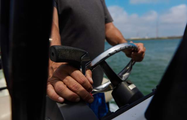 A close up of two weathered hands driving a boat