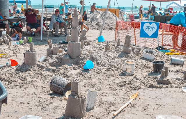 A pile of sand with various buckets and towers lying around.