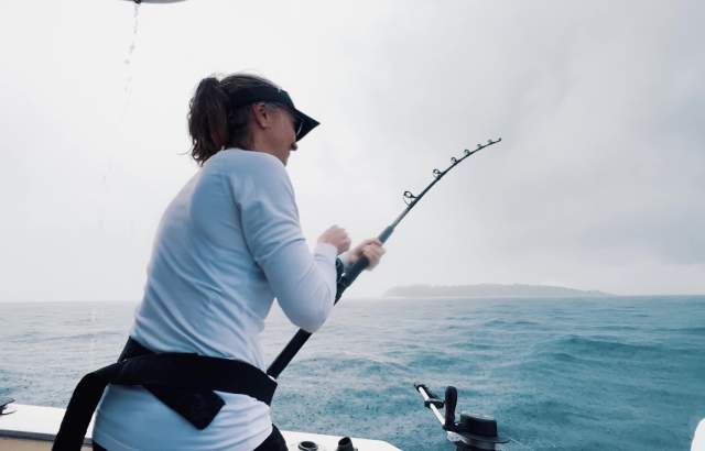 Woman fishing with a rod on a cloudy day in the waters of the Pearl Islands archipelago in Panama City.