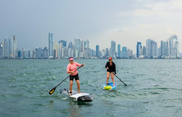 Two woman doing paddle near Taboga Island with Panama City skyline as background