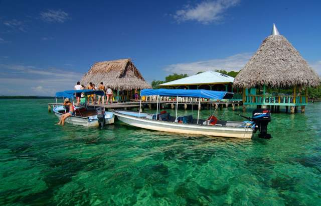 Turistas en muelle de Isla Bastimentos abordando lanchas en aguas cristalinas del Parque Nacional Marino en Bocas del Toro