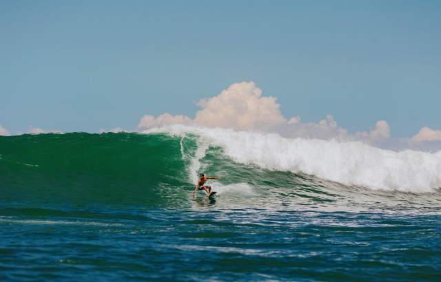 Surfer maneuvering a large wave in Panama with deep blue ocean