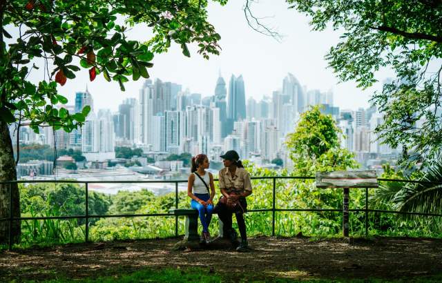 Tourists relaxing at a viewpoint in Metropolitan Natural Park with the Panama City skyline in the background.
