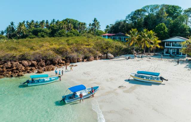 People congregated close to the waterfront of the beach with boats