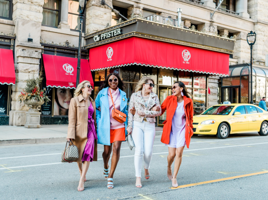 group of friends interlocking arms and walking in front of the Pfister Hotel