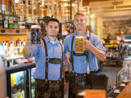 Two men in lederhosen holding liter steins of beer at the Bavarian Bierhaus