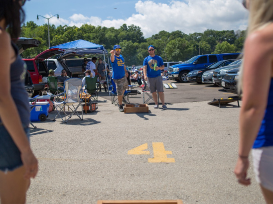 A group of Brewers fans playing a game of corn hole while they tailgate