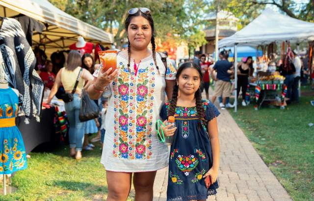 Two girls in braids and colorful dress at a festival