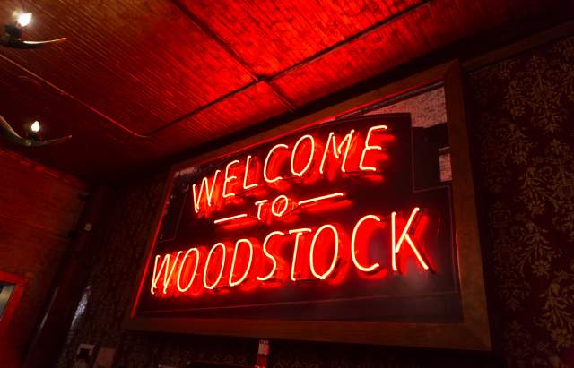 Neon Orange sign that says Welcome to Woodstock