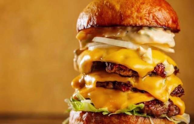 Gourmet cheeseburger topped with lettuce, tomato, and onion, served on a toasted bun at Copper Spoon restaurant in Fort Wayne.