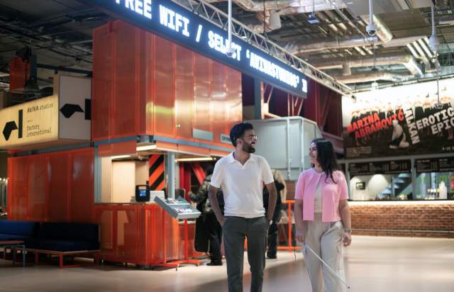 2 people walking through the lobby at Aviva Studios