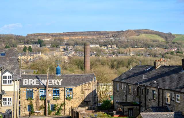 Countruyside with stone buildings and chimney with hills in background and blue sky