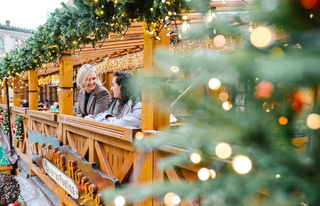 2 people stood on the balcony of Christmas markets with Christmas decorations