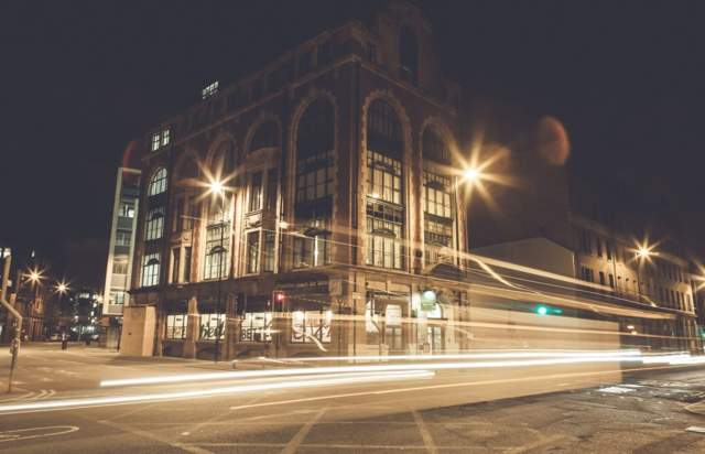 Building exterior at night with light trail of vehicle in front