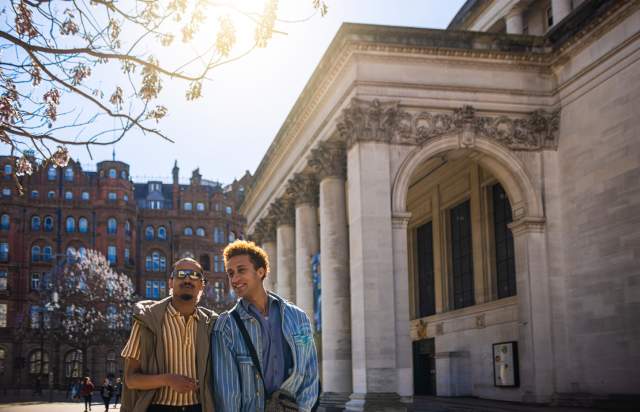2 people outside Manchester Central Library in the sun