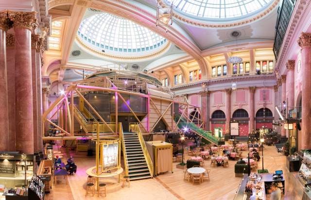 Inside the Royal Exchange Theatre with theatre space in the centre of the room and chairs and tavles set up outside