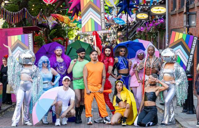 Group of people stood in colourful dress on canal street in Manchester