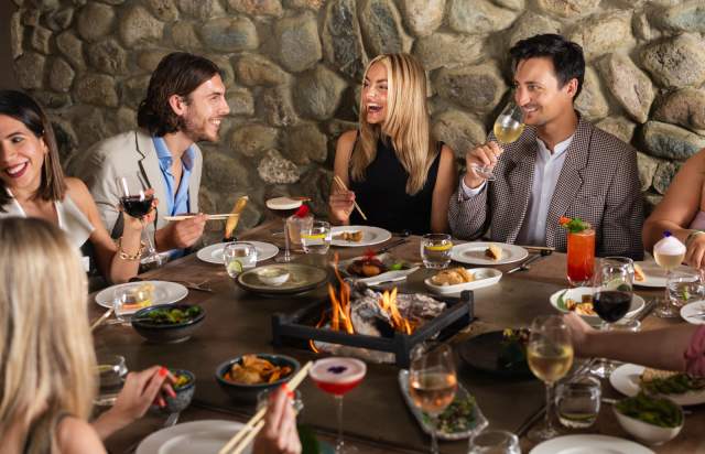 Group of people sat around table with food and drinks