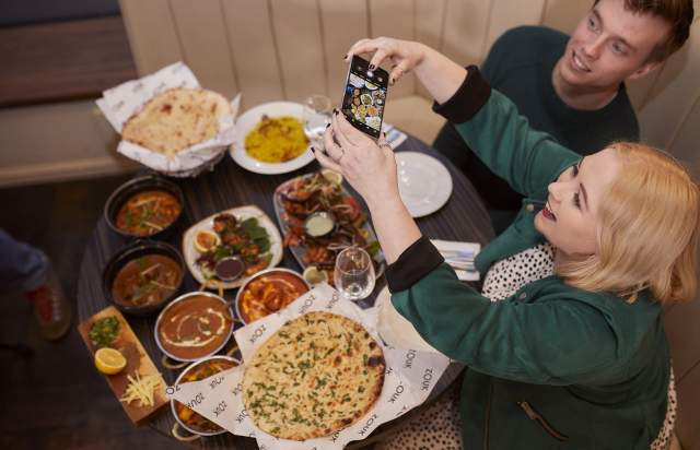 People taking photos of Indian food at a table