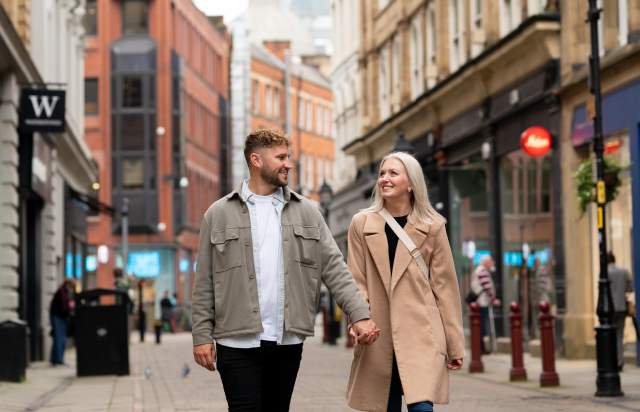 Couple hand in hand walking down a street in Manchester