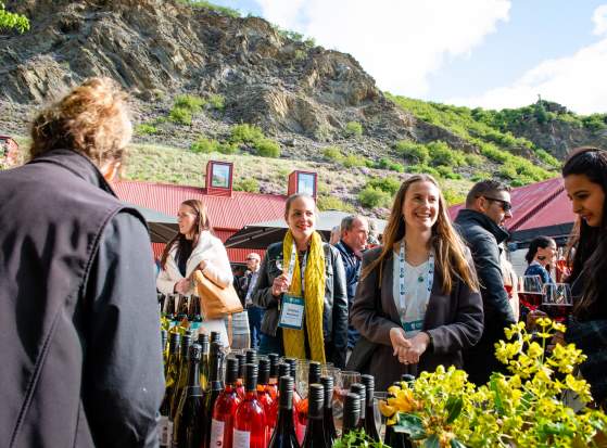A group of conference attendees standing around a wine tasting table