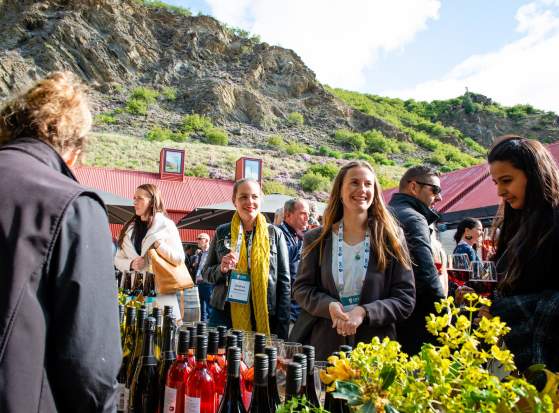 A group of conference attendees standing around a wine tasting table