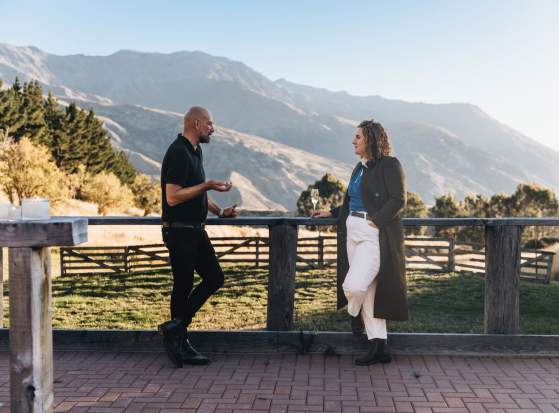 Two people networking outside with a glass of champagne and mountain view in the background