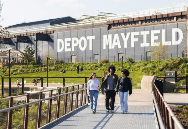 Friends walking along a bridge at Mayfield Park with Depot Mayfield sign in the background