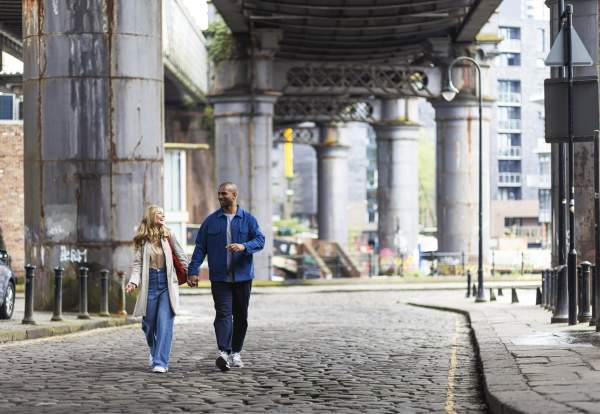People walking under bridges on cobbles streets in Manchester